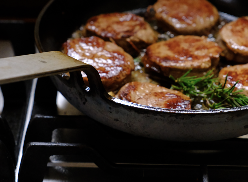 DARTO Carbon Steel Pan-seared fillet mignon cutlets cooking on a gas stove, garnished with fresh rosemary.