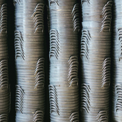 A close-up view of multiple stacked metal Paellas arranged vertically, showing their silver metallic surfaces and threaded ends.